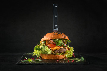 Beef burger on black background. For fast food restaurant design or fast food menu - obrazy, fototapety, plakaty
