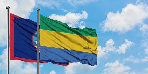 Guam and Gabon flag waving in the wind against white cloudy blue sky together. Diplomacy concept,...