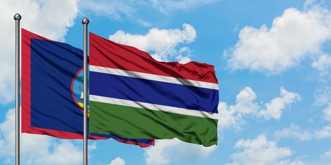 Guam and Gambia flag waving in the wind against white cloudy blue sky together. Diplomacy concept, international relations.