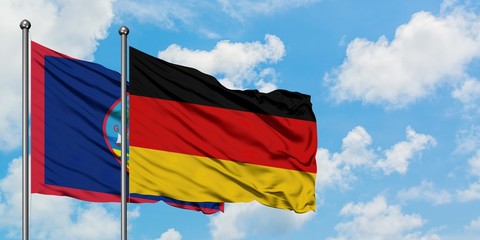 Guam and Germany flag waving in the wind against white cloudy blue sky together. Diplomacy concept, international relations.