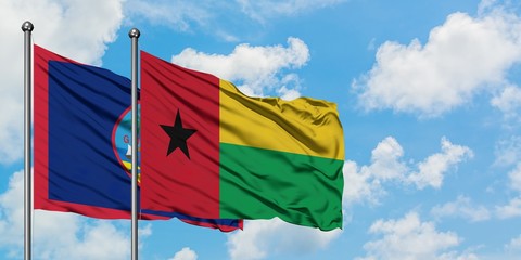 Guam and Guinea Bissau flag waving in the wind against white cloudy blue sky together. Diplomacy concept, international relations.