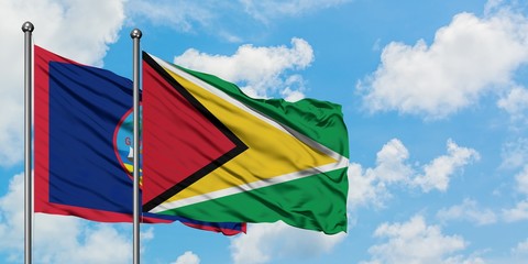 Guam and Guyana flag waving in the wind against white cloudy blue sky together. Diplomacy concept, international relations.