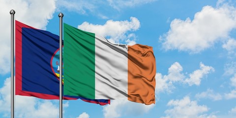 Guam and Ireland flag waving in the wind against white cloudy blue sky together. Diplomacy concept, international relations.