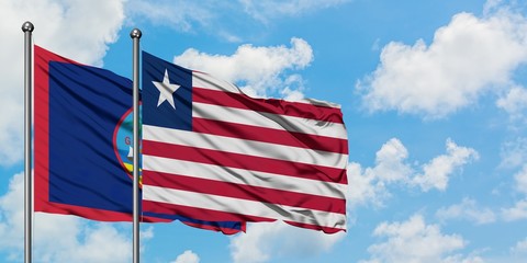 Guam and Liberia flag waving in the wind against white cloudy blue sky together. Diplomacy concept, international relations.