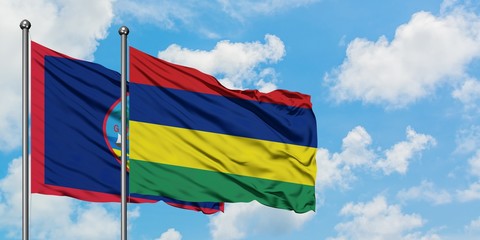 Guam and Mauritius flag waving in the wind against white cloudy blue sky together. Diplomacy concept, international relations.