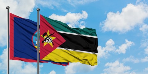 Guam and Mozambique flag waving in the wind against white cloudy blue sky together. Diplomacy concept, international relations.