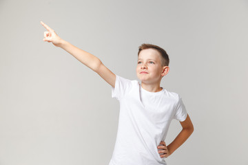 Handsome young boy stands in the pose of a hero, raising his hand up. Motivator