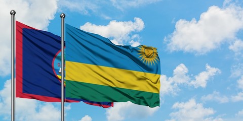 Guam and Rwanda flag waving in the wind against white cloudy blue sky together. Diplomacy concept, international relations.