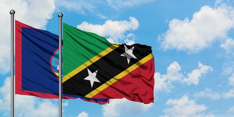 Guam and Saint Kitts And Nevis flag waving in the wind against white cloudy blue sky together. Diplomacy concept, international relations.