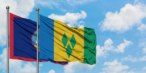 Guam and Saint Vincent And The Grenadines flag waving in the wind against white cloudy blue sky...