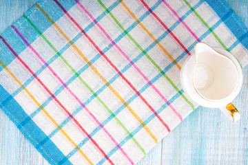 kitchen background - an empty milk jug on a napkin in blue tones, top view
