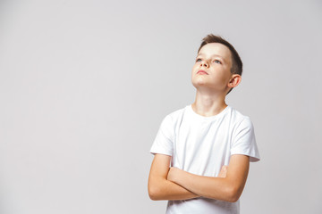 Portrait of young boy with cross arms lifting his head on white background