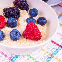 Simple delicious and healthy breakfast - bowl with oatmeal with raspberries, blueberries and blackberries