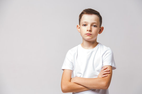 Portrait of a serious or calm caucasian boy with crossed arms wearing white t-shirt on white background