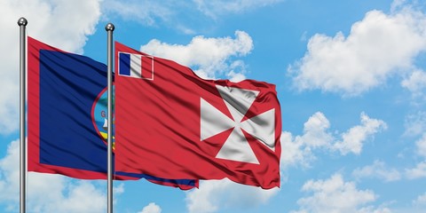 Guam and Wallis And Futuna flag waving in the wind against white cloudy blue sky together....