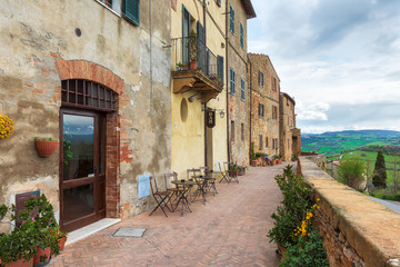 A narrow picturesque medieval street along the city wall and view to the valley in old town of Pienza in Tuscany, Italy