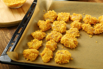 Freshly breaded in corn flakes chicken fillet on baking sheet