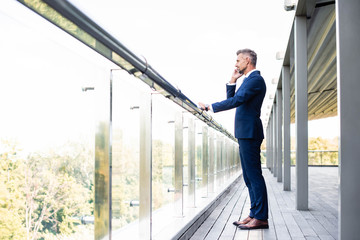 side view of handsome businessman in formal wear talking on smartphone