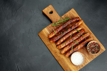 Grilled sausages with spices and rosemary on a stone table