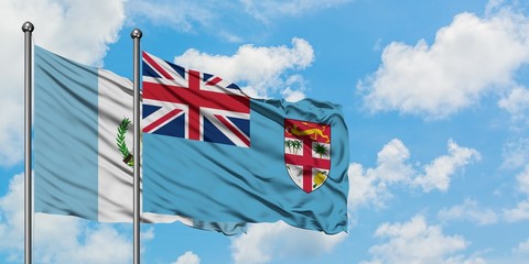 Guatemala and Fiji flag waving in the wind against white cloudy blue sky together. Diplomacy concept, international relations.