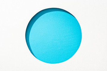 cut out round hole in white paper on blue background