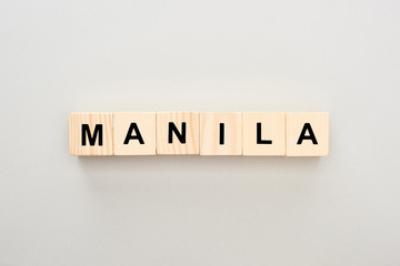 top view of wooden blocks with Manila lettering on grey background