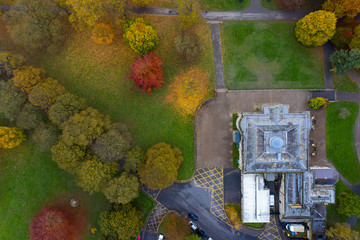 Aerial photo in autumn showing the beautiful autumn colours of a park in Leeds known as Roundhay Park in West Yorkshire UK showing The Mansion Hotel and carpark leading in to the parl.