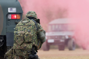 装甲車の陰で銃を構える自衛官