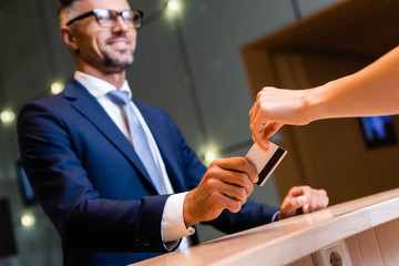 handsome businessman in suit and glasses giving credit card to woman