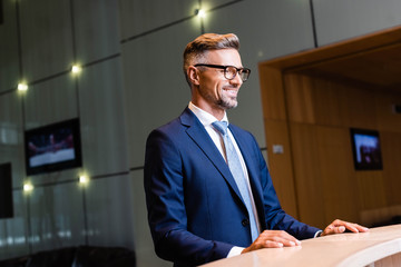 handsome businessman in suit and glasses smiling and looking away