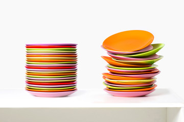 The piles of multi-color plates lyes on a white table