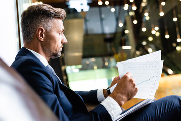 side view of handsome businessman in suit looking at papers