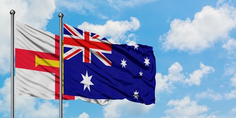 Guernsey and Australia flag waving in the wind against white cloudy blue sky together. Diplomacy concept, international relations.