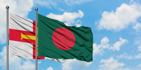 Guernsey and Bangladesh flag waving in the wind against white cloudy blue sky together. Diplomacy concept, international relations.