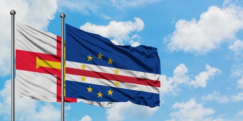 Guernsey and Cape Verde flag waving in the wind against white cloudy blue sky together. Diplomacy concept, international relations.