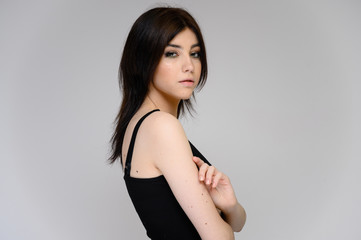 Fototapeta premium Close-up portrait of a young pretty girl student with long black hair, on a white background. He stands right in front of the camera, showing his hands in different poses with different emotions.