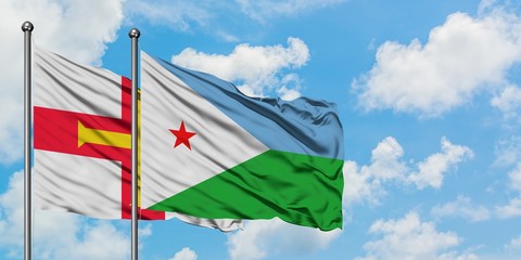 Guernsey and Djibouti flag waving in the wind against white cloudy blue sky together. Diplomacy concept, international relations.