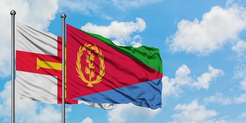 Guernsey and Eritrea flag waving in the wind against white cloudy blue sky together. Diplomacy concept, international relations.