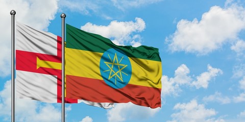 Guernsey and Ethiopia flag waving in the wind against white cloudy blue sky together. Diplomacy concept, international relations.