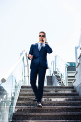 handsome man in suit and glasses talking on smartphone