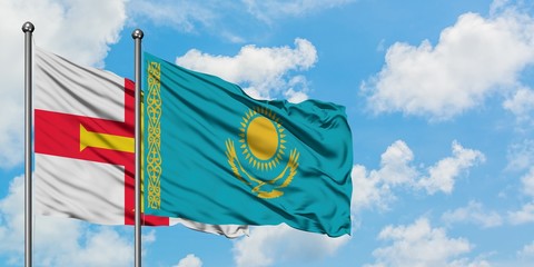 Guernsey and Kazakhstan flag waving in the wind against white cloudy blue sky together. Diplomacy concept, international relations.