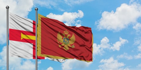 Guernsey and Montenegro flag waving in the wind against white cloudy blue sky together. Diplomacy concept, international relations.