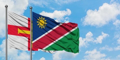 Guernsey and Namibia flag waving in the wind against white cloudy blue sky together. Diplomacy concept, international relations.