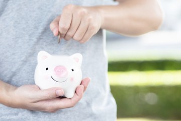 hand putting coin into piggy bank