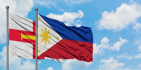 Guernsey and Philippines flag waving in the wind against white cloudy blue sky together. Diplomacy concept, international relations.