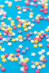 party, sweets and decoration concept - star shaped sugar sprinkles on blue background