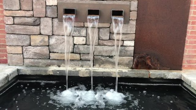 Close up of water flowing from wall fountain with vintage bricks as background