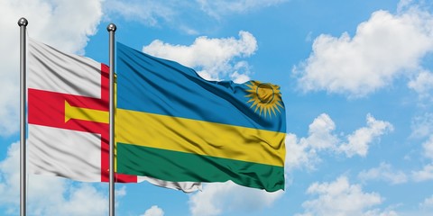 Guernsey and Rwanda flag waving in the wind against white cloudy blue sky together. Diplomacy concept, international relations.