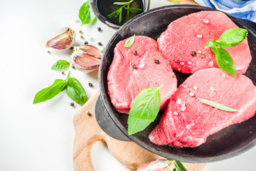 Raw fresh meat. Beef meat steaks with spices and herbs, white background top view copy space