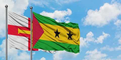 Guernsey and Sao Tome And Principe flag waving in the wind against white cloudy blue sky together....
